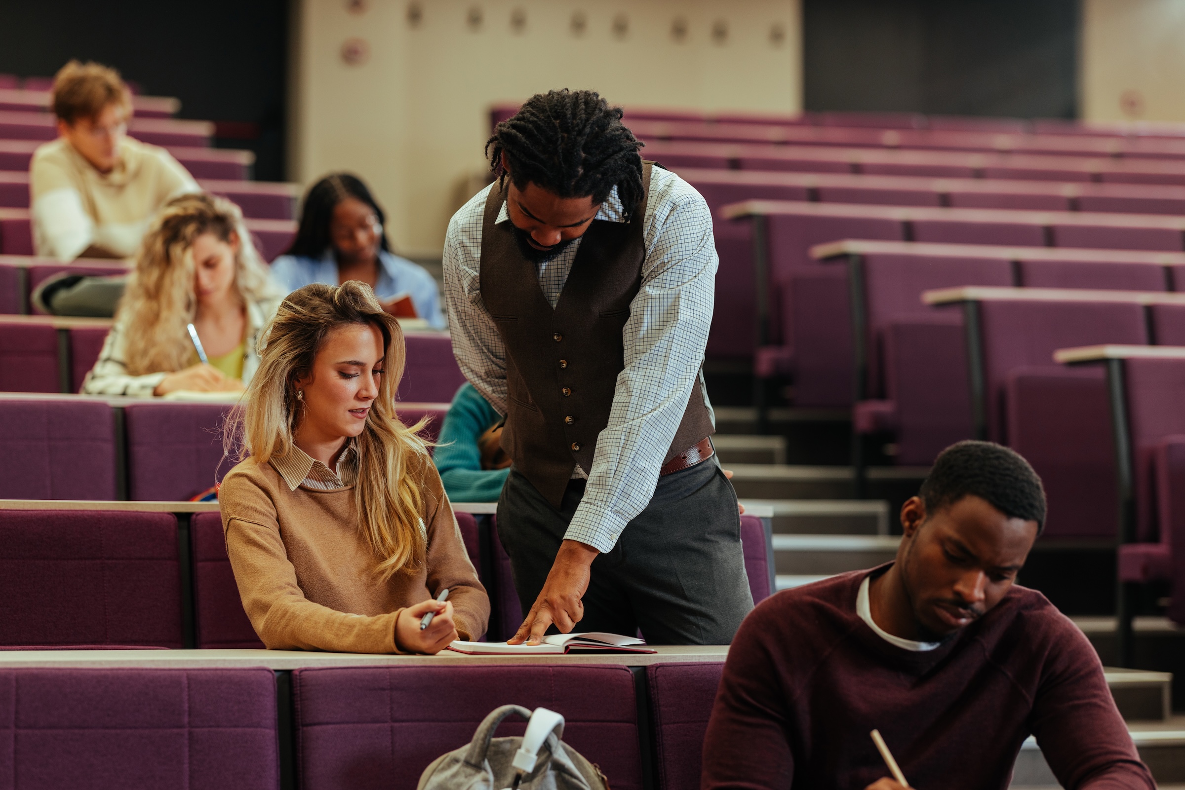 A professor engages in conversation with a student in a seminar setting