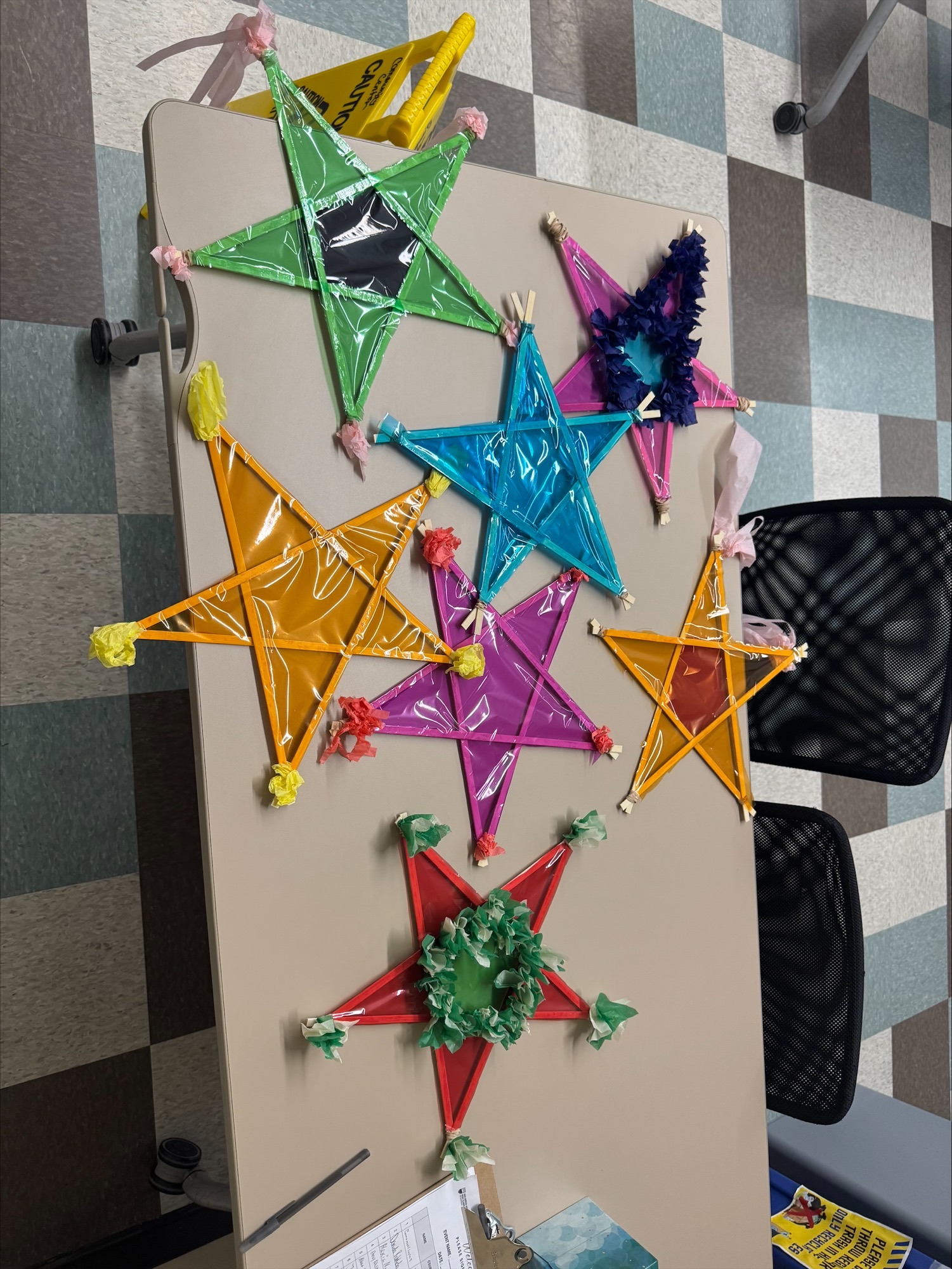 Brightly decorated stars, known as Philippine parols, made out of bamboo sticks, cellophane, and tissue paper decorate a table.